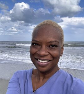 Rita Lynn Berry smiling at the ocean, representing compassionate therapy and healing for women in North Carolina.